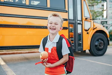 Childrens health image child holding apple by schoolbus