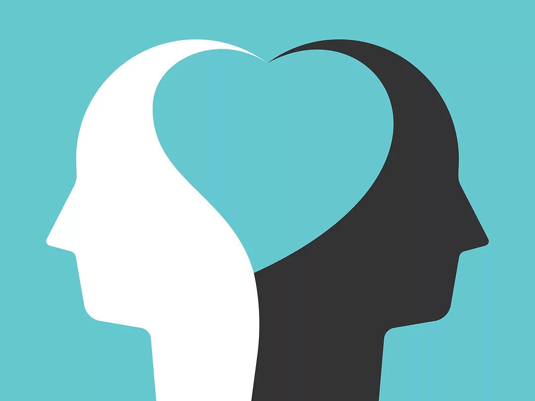 Two white and black head silhouettes united by heart shape inside them on turquoise blue. Unity, peace, love concept.