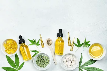 cbd oil, capsules and tablets with cannabidiol and cannabis leaves on gray concrete table