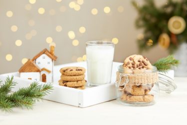 A glass of milk and Christmas cookies on the table against the background of bokeh lights