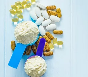 Closeup blue and purple measure dishes with protein powder and white-yellow sport pills around on the white table