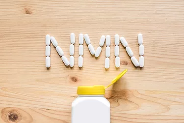 Nicotinamide mononucleotide. White pills forming shape to NMN alphabet on wooden background.
