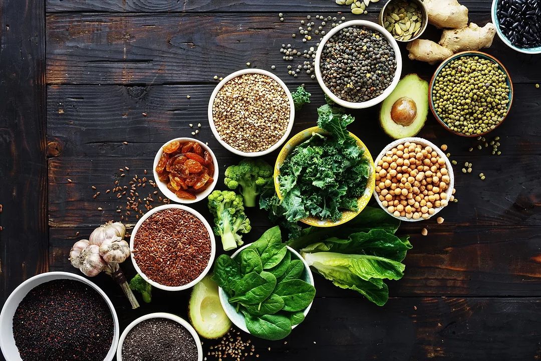 Superfoods on dark wooden table. Leaves, cereals and seeds top view. Healthy vegetarian food