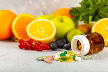 Vitamins and supplements. Variety of vitamin tablets in a jar on a texture background.Multivitamins with fresh and healthy fruits.