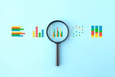 Magnifying glass and various business graphs on light blue background
