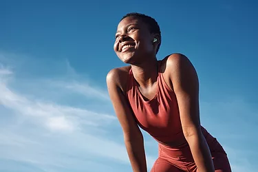 Happy athlete smile after running, exercise training workout. Blue sky, summer sports and runner breathing with happiness from sport outdoor.