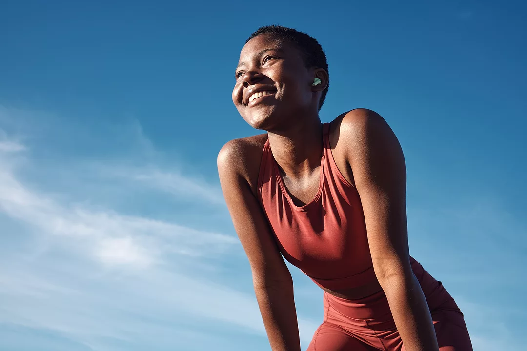 Happy athlete smile after running, exercise training workout. Blue sky, summer sports and runner breathing with happiness from sport outdoor.
