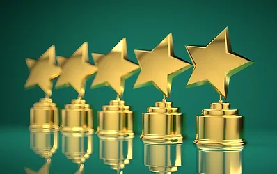 Row of gold star trophy awards on green background.