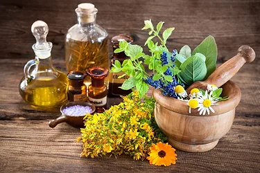 Essential oil, mortar with fresh herbs and bath salt on wooden background