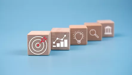 wooden block which prints a target icon and business symbol on light blue background. Business goals and objectives concept. business competition.