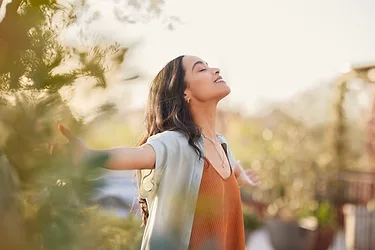 Mindful woman enjoying morning ritual while relaxing in outdoor park.