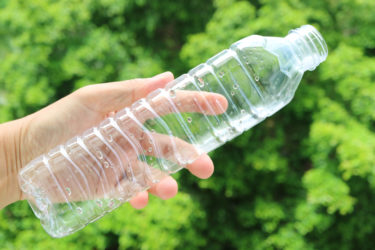 Plastic Water Bottle being held in grassy setting.