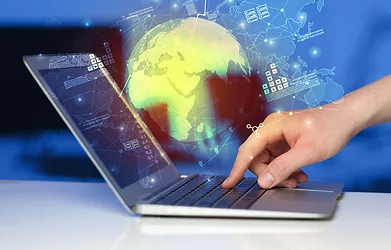 Hand using laptop with global reports and stock market change concept.