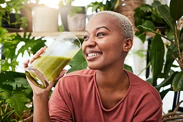 Happy woman drinking Vegan Green Smoothie