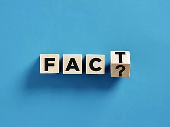 Four wooden cubes with fact and question mark sign on blue background are representing questioning facts concept.
