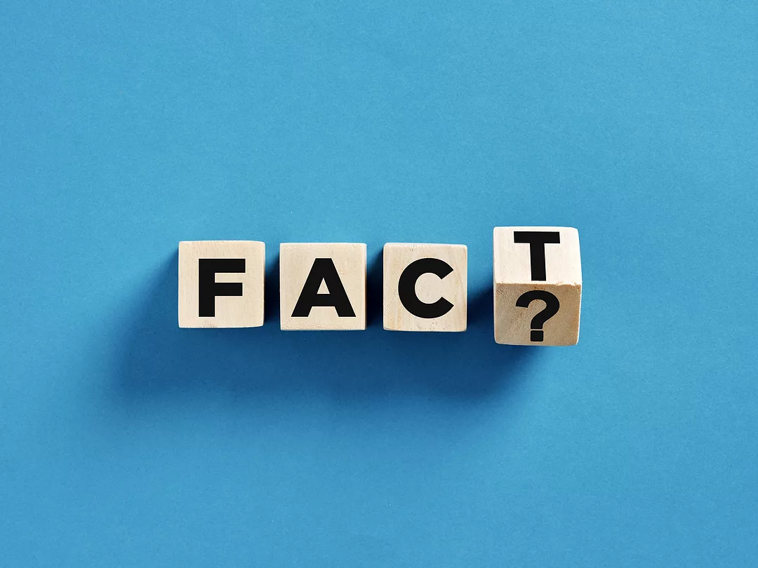 Four wooden cubes with fact and question mark sign on blue background are representing questioning facts concept.