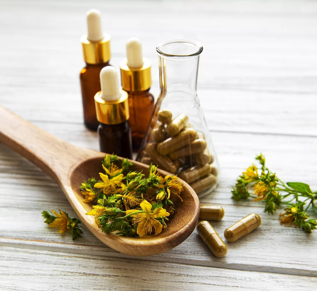 St. John's wort herbal supplement in test tube, bottles with natural oil on a table