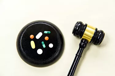 Judge's gavel and pills on a light green background. 