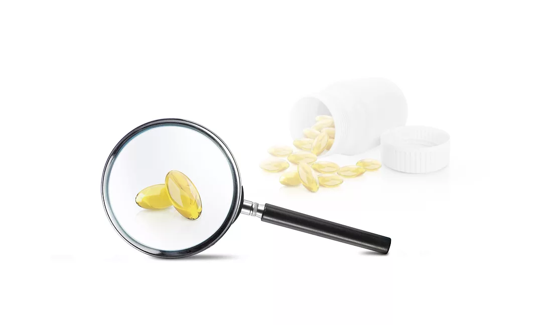 Supplements shown under a magnifying glass, symbolizing increased scrutiny of regulatory oversight and product transparency in the dietary supplement marketplace.